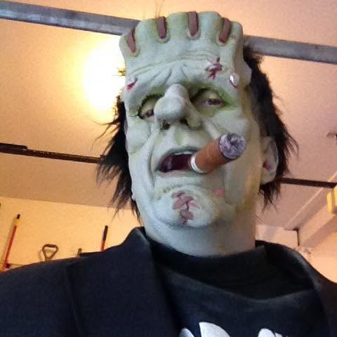 Geno in a Frankenstein mask, smoking a cigar